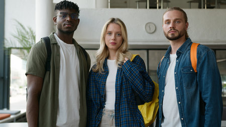 Portrait university college academy studying together education three students multiracial friendship multiethnic friends male men Caucasian African American guys woman girl female looking at cameraの写真素材