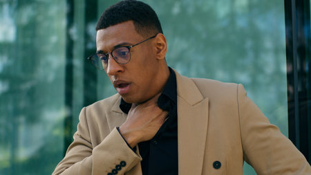 African American man business entrepreneur businessman guy male in city coughing sick suffer from pneumonia inflammation of lungs ill unwell fever cold virus flue throat pain medicine health problemの写真素材