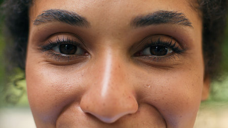 Cropped view close up female dark eyes vision eyesight laser correction African American happy woman smiling healthy looking at camera health medicine girl lady face look gaze in city urban outdoorsの写真素材