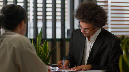 Two business men colleagues signing contract agreement happy deal cooperation partnership African American businessmen in office ethnic man guy male sign paper document bank insuranceの写真素材