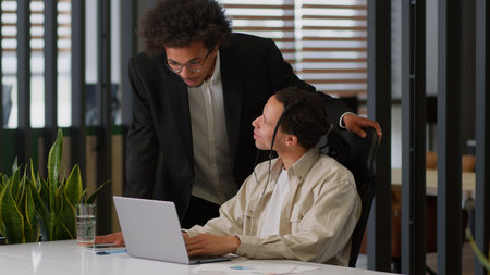 Business intern worker man working with laptop in office African American leader boss mentor coming help talking together two diversity businessmen colleagues discuss internet web data difficultyの写真素材