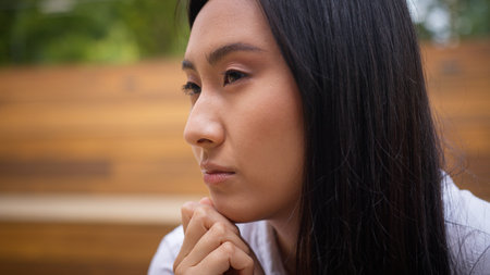 Close up face thoughtful pensive Asian Korean Chinese Japanese woman looking at camera female girl businesswoman outdoor sad upset student worker think solution portrait employer business bored cityの写真素材