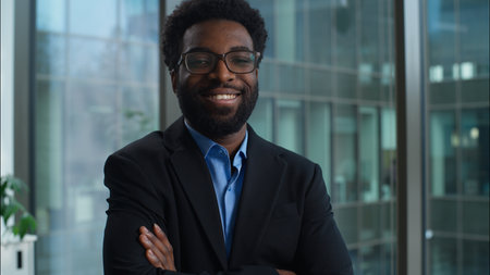Happy successful African American man in glasses businessman smiling looking at camera portrait business manager crossed arms male confident toothy dental smile worker employee leader guy in officeの写真素材