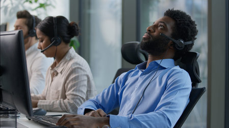 Frustrated multiethnic operators callcenter business crisis computer headache Caucasian African men...