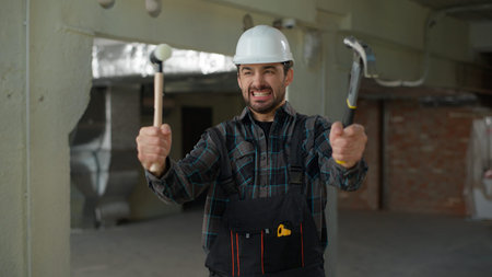 Builder emotional man Caucasian guy engineer repairman holding hammers tools repair work industry...