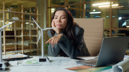 Sad tired business woman Asian girl businesswoman exhausted boring work wind turbine energy production engineering project in office Chinese Korean Japanese designer architect manager burnout boredの写真素材