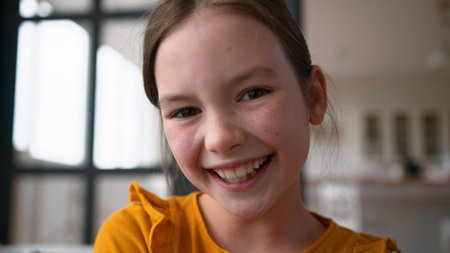 Joyful Caucasian child portrait schoolgirl girl close up looking at camera posing. Happy kid little daughter feeling cheerful emotion at home healthy white smile wellbeing custody adoption pediatricの写真素材