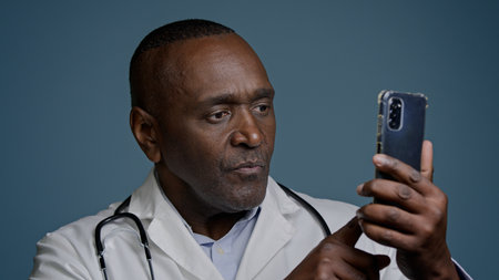 African American man male doctor in white uniform typing answer sending email message on smartphone browsing patient card using medical virtual application on mobile phone medicine and modern techの写真素材