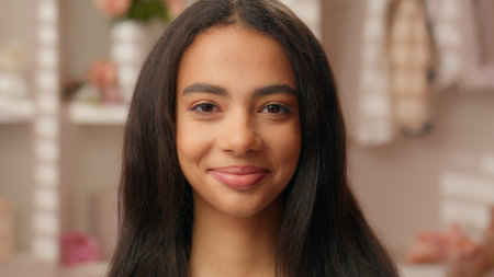 Portrait beautiful ethnic Latina Hispanic woman teenager serious emotion girl close up face makeup routine healthy skin hair care in pink bathroom female looking at camera fashion model health medicalの写真素材