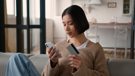 Caucasian hispanic woman thoughtful pensive girl female homeowner buyer shopper shopping online internet store purchase think choose order delivery at home buy pay credit card mobile phone bank appの写真素材