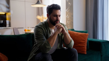 Nervous thoughtful Caucasian business man male guy client homeowner businessman sitting sofa folded...