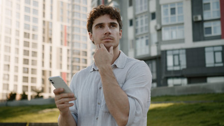 Pensive Caucasian man using mobile phone smartphone thinking thoughtful guy ponder looking around...