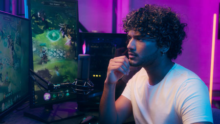 Thoughtful Arabian Indian man gamer playing video game cyber sport computer streamer male thinking...