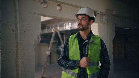 Serious Caucasian builder guy holding hammer in construction technician electrician repairman throw...