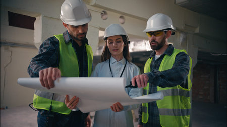 Three Caucasian colleagues coworkers contractors males looking scheme engineering in factory female...