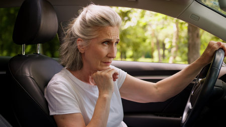 Angry frustrated disappointed Caucasian woman lady senior mature aged female client car driver in automobile cant start engine starting broken vehicle repair problem hit steering wheel anger annoyedの写真素材