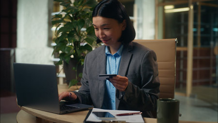 Asian Korean Chinese Japanese woman typing laptop holding banking credit card payment order buying...