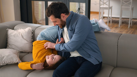 Cheerful Caucasian daughter little child surprise hug embracing distracting dad parent male father...