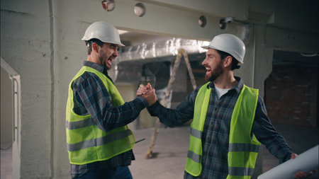 Two happy Caucasian men greeting friends buddies males guys workers in uniform helmets business...