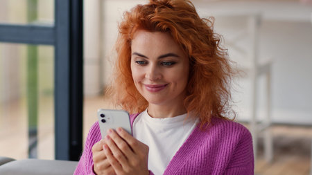 Smiling happy Caucasian woman user wife girl female at home couch using cellphone apartment looking...