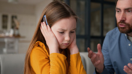 Anxious Caucasian daughter schoolgirl child closing ears annoyed dad guy male man screaming furious parent father scolding fearful little girl kid at home family conflict argue punishmentの写真素材