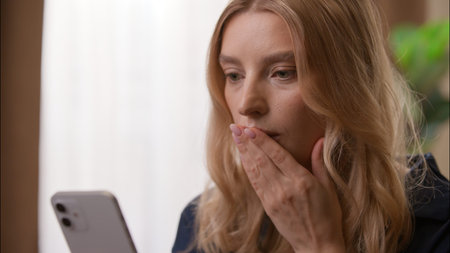 Anxious disappointed Caucasian female reading negative news mobile phone bankruptcy in bedroom woman...