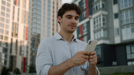 Caucasian man going walking using mobile phone smartphone online social media technology networks internet employee male guy businessman city outdoors gadget holding device cellphone worker businessの写真素材