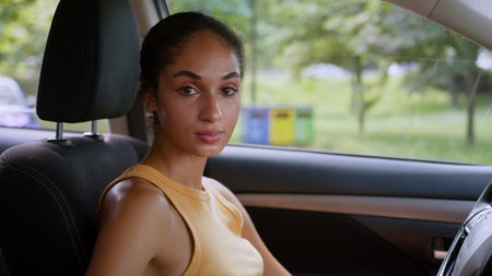 Confident serious successful African American businesswoman woman turning head looking at camera indoor car auto automobile female vehicle owner driver girl portrait lady business buyer transportationの写真素材