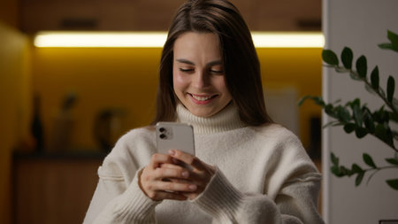 Happy Caucasian woman chatting at home using mobile phone smartphone female smiling texting online...