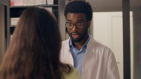 Pharmacy cashier counter African American man pharmacist reading medical prescription receipt buying medicine in drugstore woman buyer order pills medicaments health care worker help customer advisingの写真素材