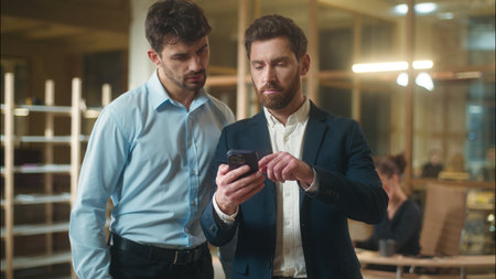 Happy businessmen colleagues friends male business partners guys fellows Caucasian men funny laughing together use mobile phone in office break humor meet friendship laugh smartphone message good newsの写真素材