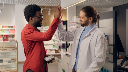 Pharmacy professional assisting customer medical help doctor pharmacist advice recommend medicine pills drugs vitamins health care prescription African Caucasian multiracial men clapping hands dealの写真素材