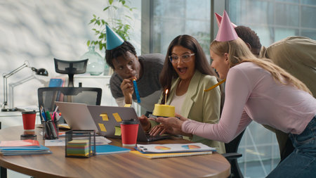 Indian businesswoman Arabian woman working laptop in office three multiracial business colleagues make surprise celebrating congratulate with birthday cake diversity informal startup workers gift