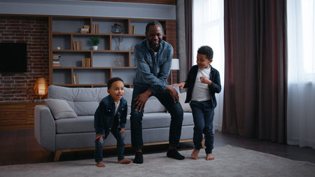 Happy African American family dancing at home father dad with two lovely children sons boys kids...