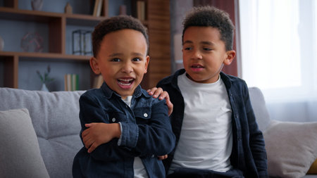 African American boys quarrel at home family brother sorry apologize after conflict problem calming upset sad funny little child pretending frustrated offended two siblings kids sons children friendsの写真素材