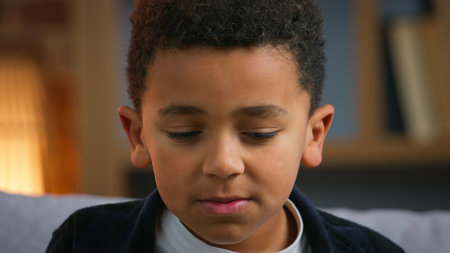Closeup upset little African American boy child looking down feeling bad stressed bored unhappy ashamed disappointed kid son family loneliness at home childhood sorrow negative emotion suffering sadの写真素材