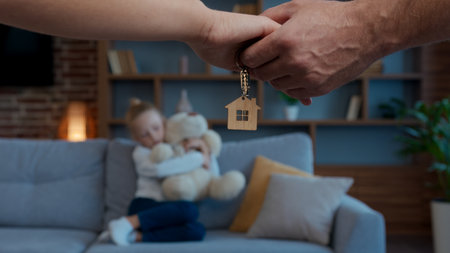 Happy Caucasian family relocation buying new home couple parents hands holding keys daughter child kid playing on backgroundの写真素材