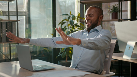 Successful businessman African American business man finish computer work end online project close laptop job done pause freedom break relaxing in office stretching hands arms stretch resting relaxの写真素材