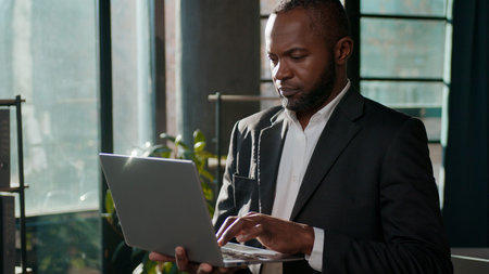 African American ethnic business man concentrated businessman typing laptop online software chatting...