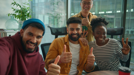 Point of view from phone web camera four diversity coworkers informal business group of managers making selfie photo having fun in office showing thumbs up casual joyful multiethnic peopleの写真素材