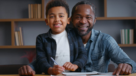 African American family smiling portrait study looking at camera ethnic father dad with little son kid child boy studying learning at table writing homework distant education video call positive lookの写真素材