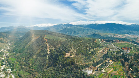 Drone flying aerial view Granada Sierra Nevada mountains landscape green hills blue skyline beautiful nature olive groves historic Alhambra travel Andalusian countryside Spanish tourism destinationの写真素材