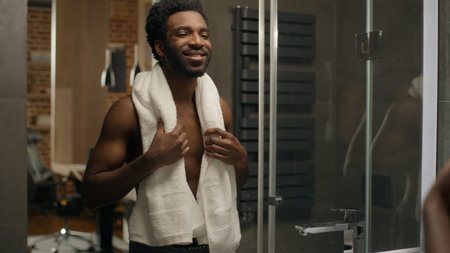 Ethnic man in bathroom beard shaving face bearded guy looking at mirror reflection shave grooming morning hygiene smiling male facial moisturize lotion gel cream soft skin cosmeticsの写真素材