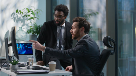 African American Caucasian men chatting talking break relax team businessmen business males looking computer monitor winning good news successful deal celebrate guys happy coworkers colleagues officeの写真素材