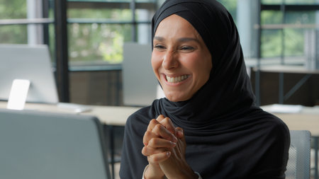 Islamic ethnic happy business woman winning online achievement celebration businesswoman in hijab in office win victory internet computer good news Muslim female girl with pc work surprised smilingの写真素材