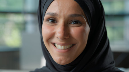 Portrait in office happy business woman in hijab looking at camera smiling toothy Islamic...