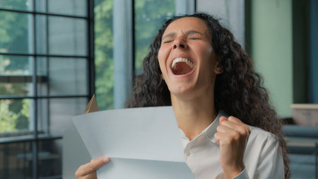 Hispanic business woman opening paper envelope reading good news amazed rejoice letter businesswoman female girl read information happy yelling joyful invitation bank credit approvalの写真素材