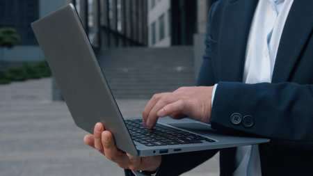 Close up male hands typing laptop in city unrecognizable business man holding wireless computer device gadget in downtown unknown businessman entrepreneur working with internet cyberspace online appの写真素材