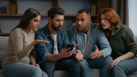 Four multiracial friends at home party looking in mobile phone lost bet casino failure confused sad diversity multiethnic people men women watching sport game streaming on smartphone bad result shockの写真素材