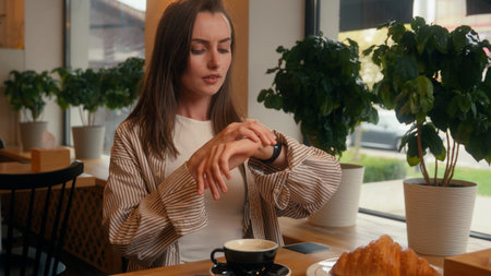 Worried Caucasian woman in cafe looking in window checking time with wristwatch confused waiting date girl female at cafeteria table shrug shoulders impatient businesswoman lateness business meetingの写真素材